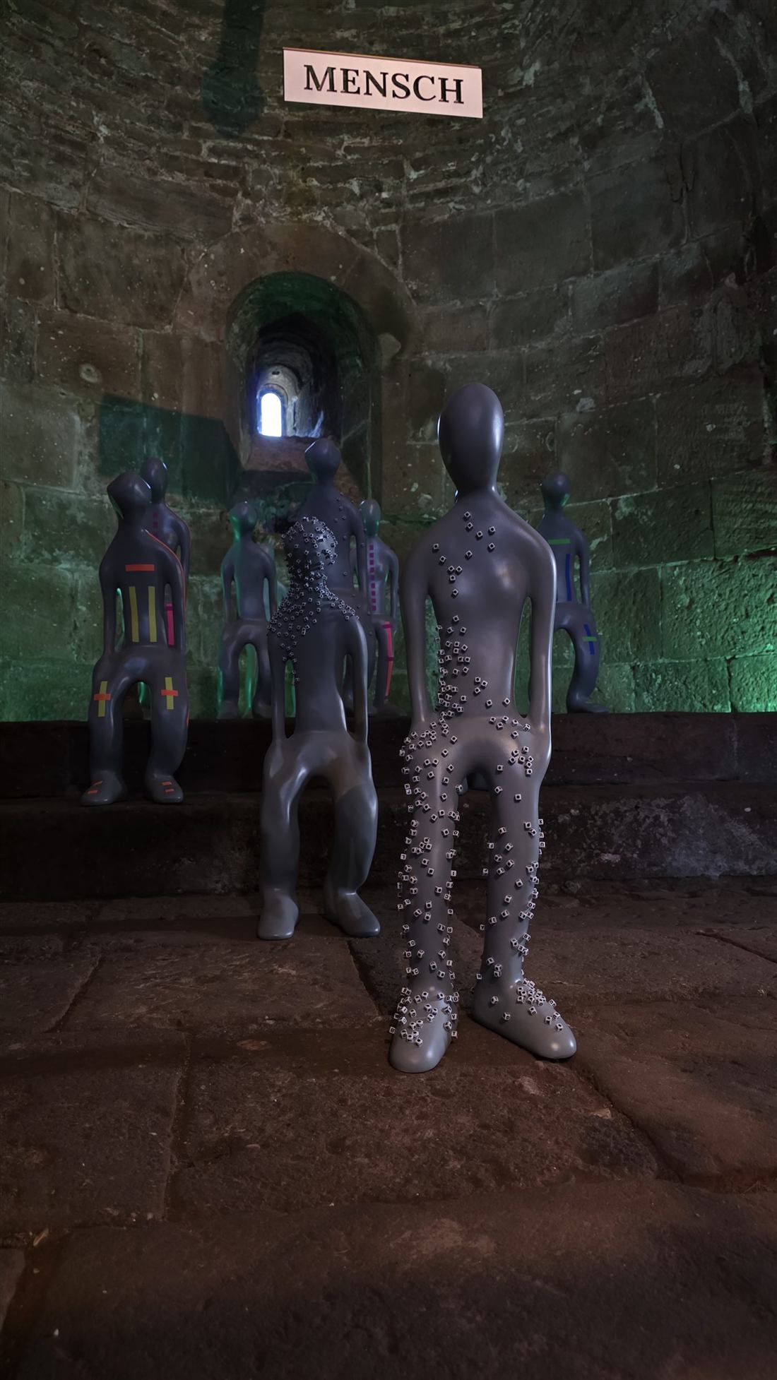 Figuren im Gewölbe der Burg Nideggen unter dem Schriftzug MENSCH